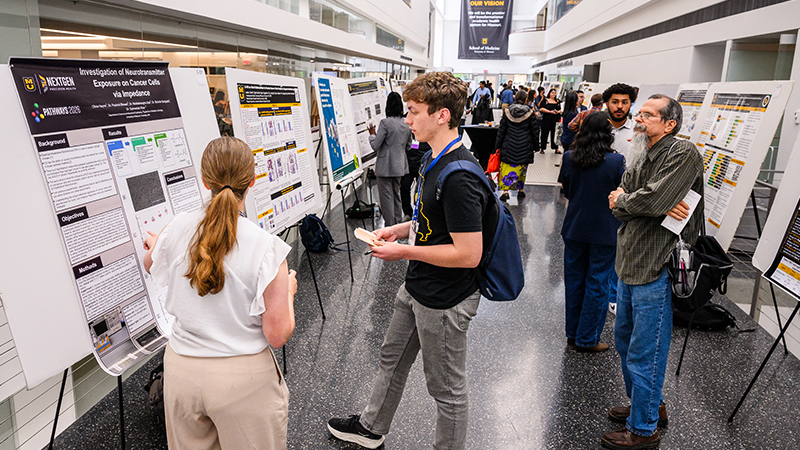 A photo of people reviewing posters during the Cancer Research Day.